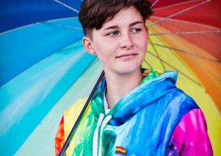 Foto jongeman met regenboogparaplu