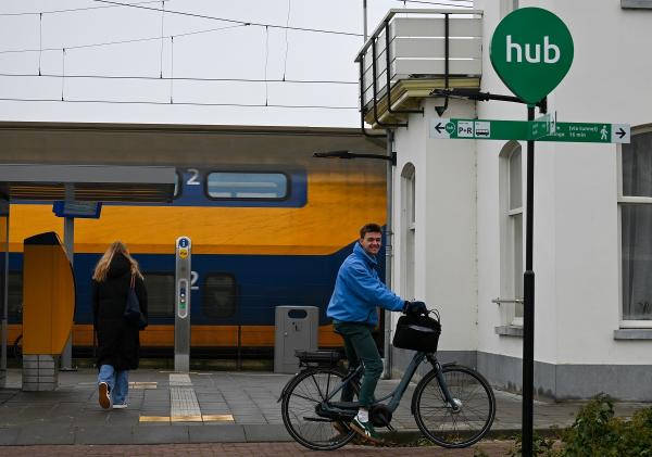 Trein, fietser, voetganger op perron en bordje HUB