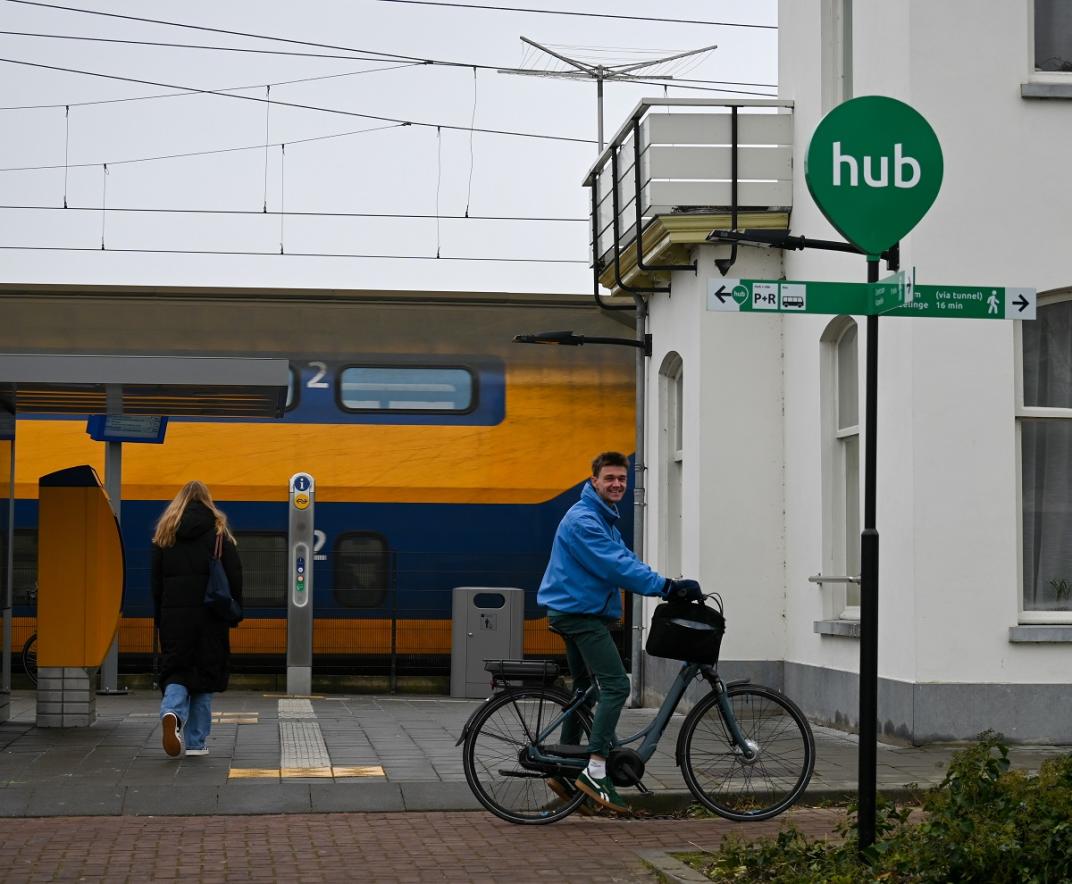 Trein, fietser, voetganger op perron en bordje HUB