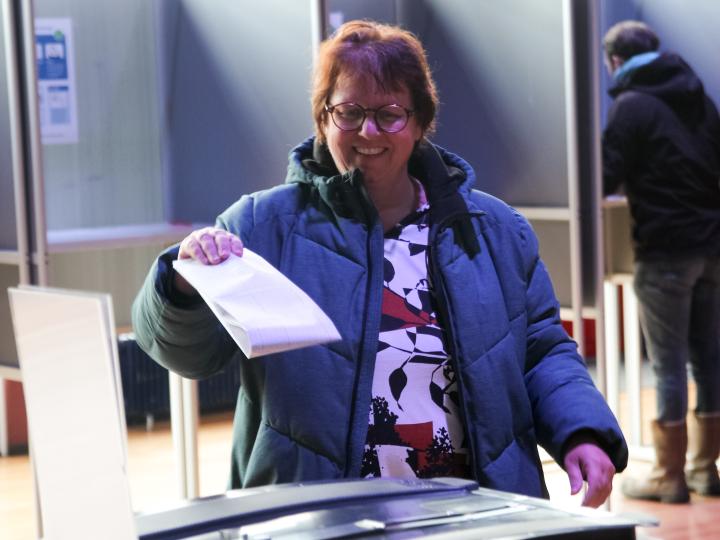 Vrouw stopt stembiljet in stembus