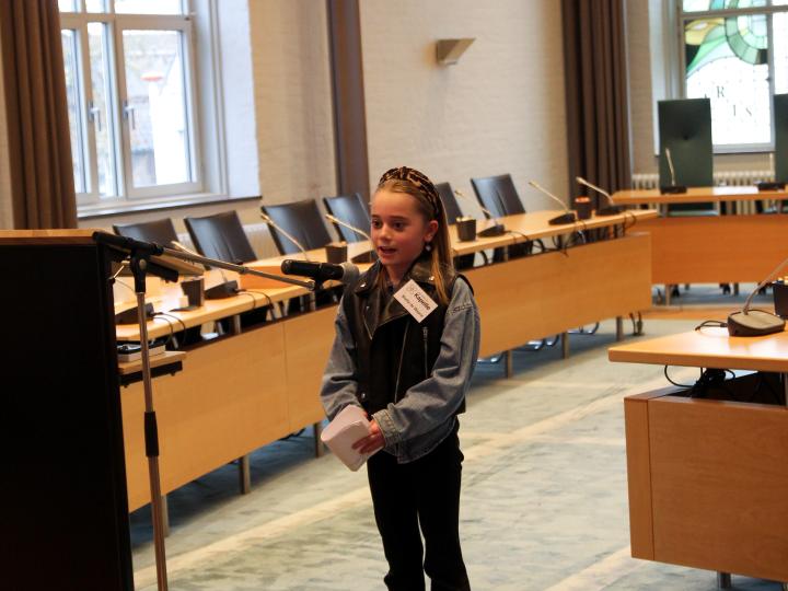 Meisje geeft toespraak in gemeentehuis voor kinderburgemeester verkiezing
