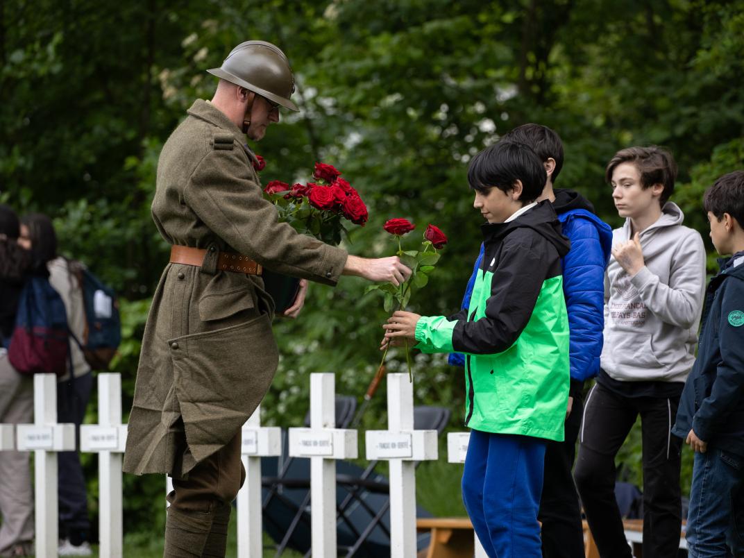 Basisschoolkinderen leggen rozen op de graven