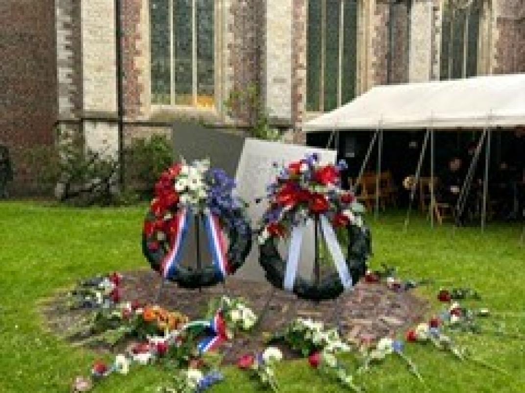 Twee kransen voor het monument met de kerk op de achtergrond