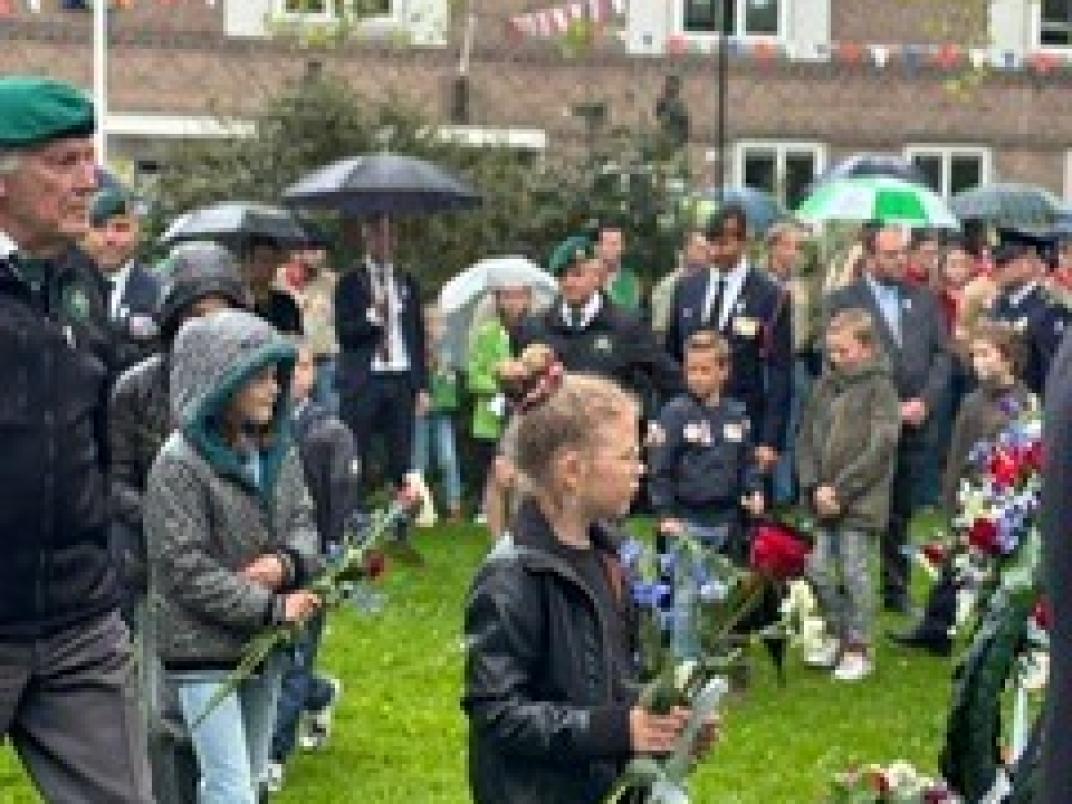 Kinderen met roos in hun hand lopen naar monument