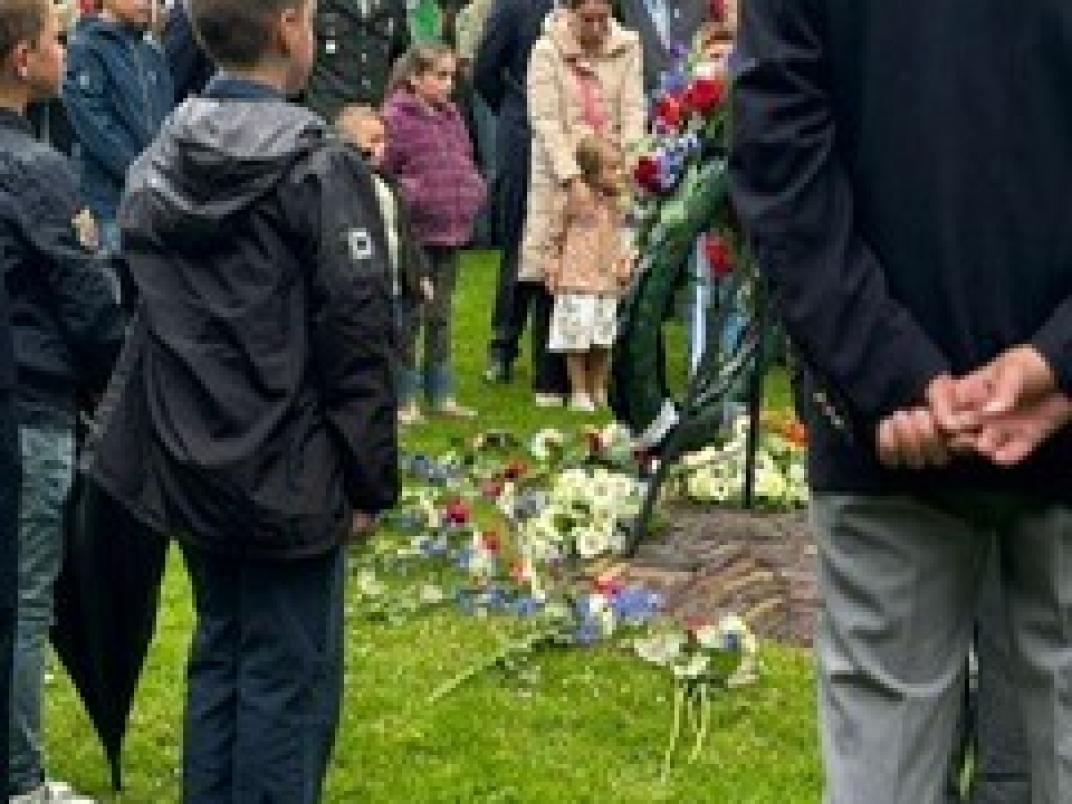 Grote groep mensen en kinderen rondom monument