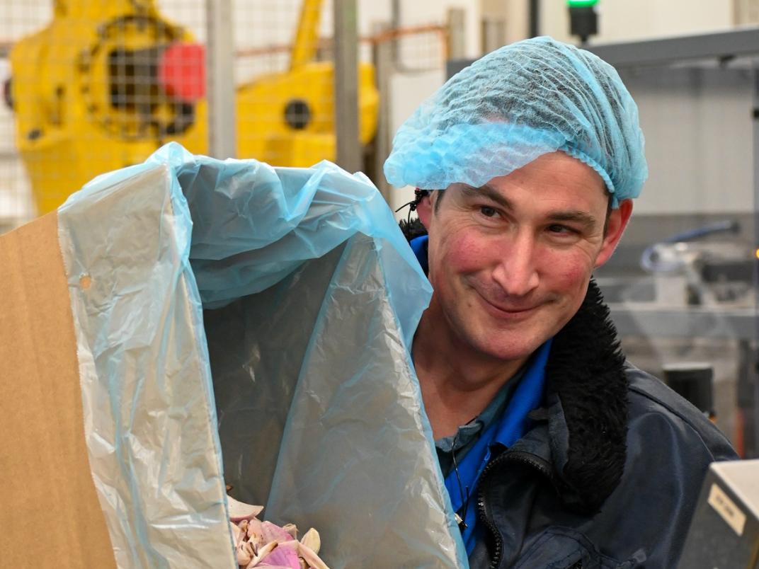 Medewerker Farm Pack houdt een kartonnen doos met gesneden uien vast