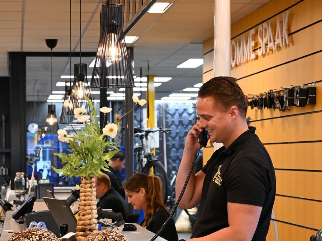 Medewerker fietsenwinkel aan de telefoon