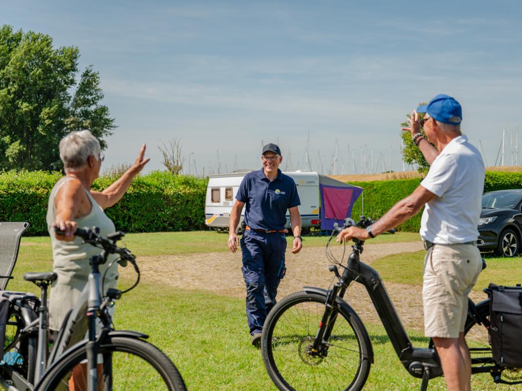 Twee gasten met de fiets zwaaien naar Emanuel Dekker