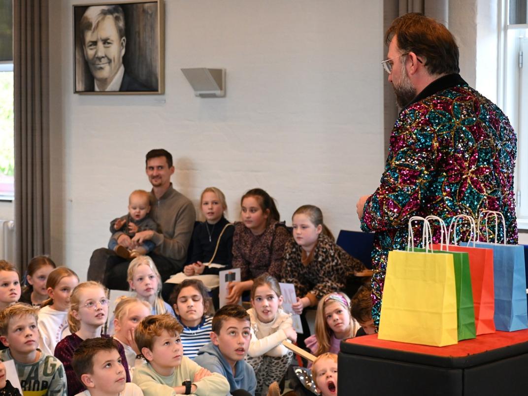 Goochelaar die wat aan kinderen in het publiek verteld