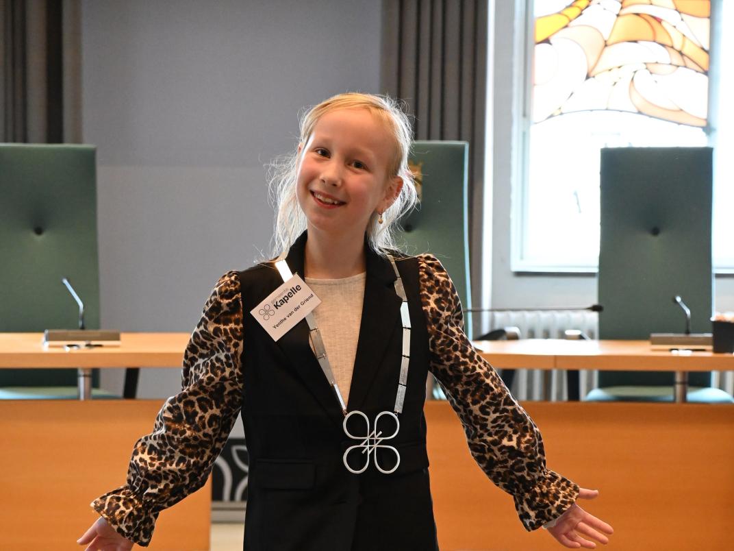Kinderburgemeester Yenthe met de keten om met daaraan het logo in de vorm van bloesem