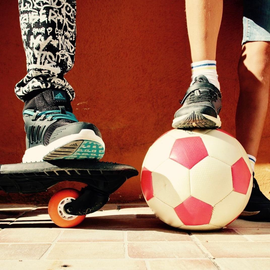 Kindervoeten met skateboard en voetbal