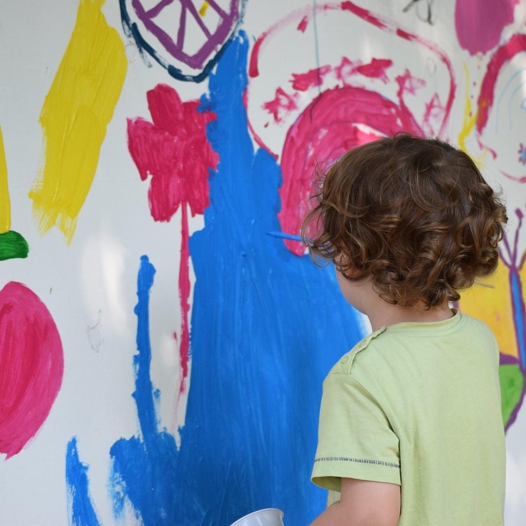 Kind is aan het schilderen op de muur tijdens naschoolse activiteiten